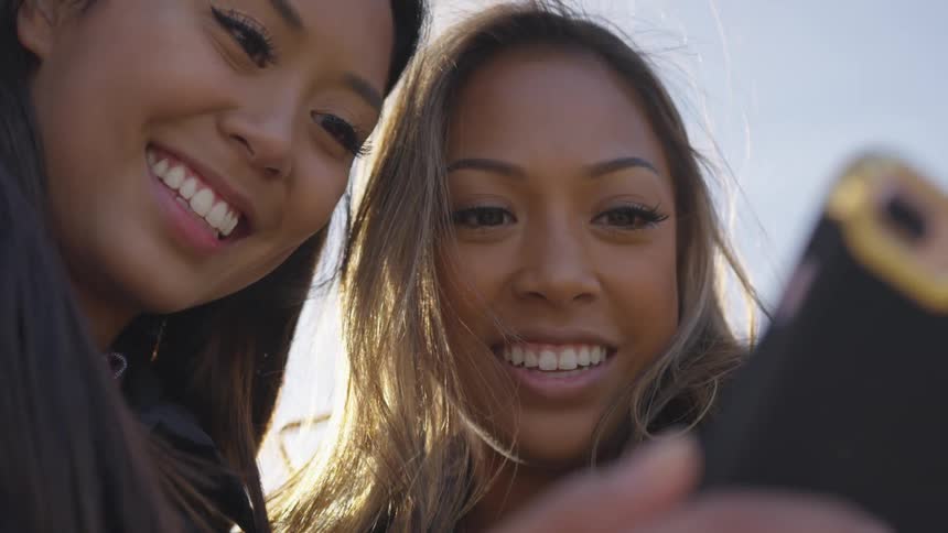 Women view mobile phone smiling intently