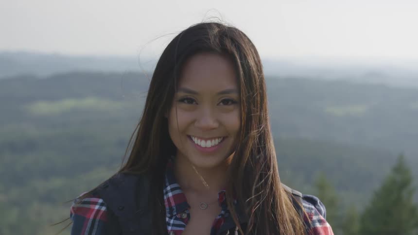 A woman is smiling outdoors