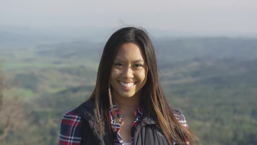 A woman is standing outdoors and smiling