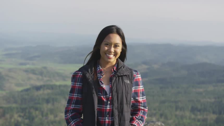 A woman is standing outdoors near a forest