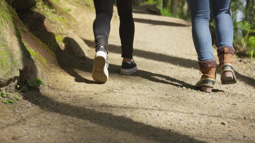 Two people walk together on a dirt trail
