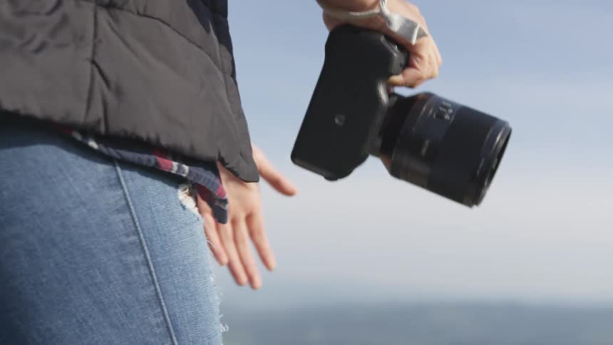 A woman raises a camera to her eye to take a picture