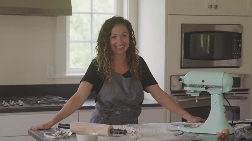 Young woman smiles at the camera while standing in the kitchen at home