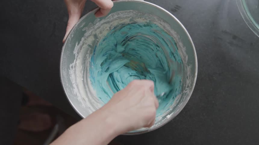 A person mixing icing in a bowl
