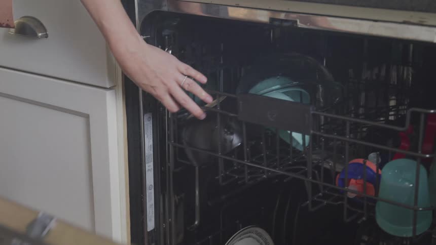 Placing large glass bowl in dishwasher then drying hands after closing door