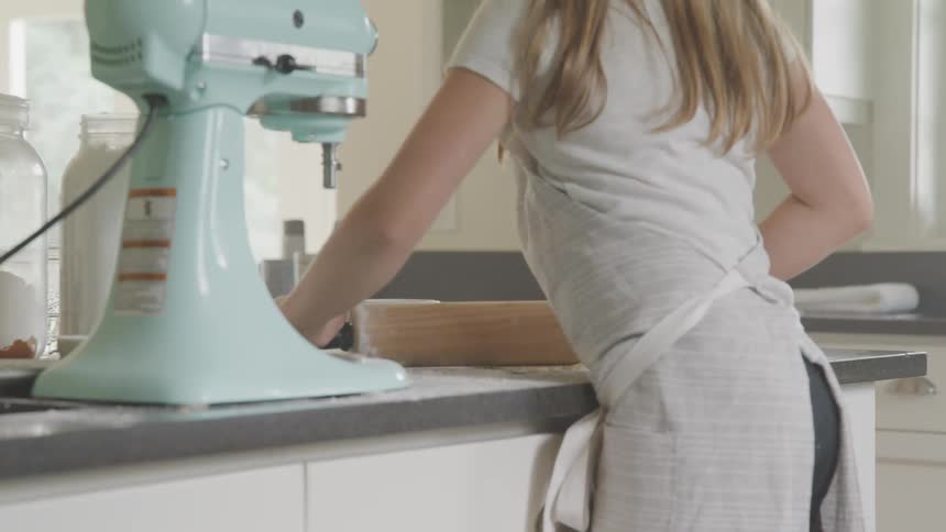 Rolling out dough with rolling pin on counter next to mixer