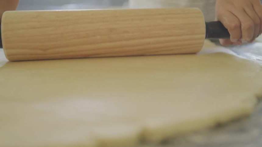 A person is flattening out some dough
