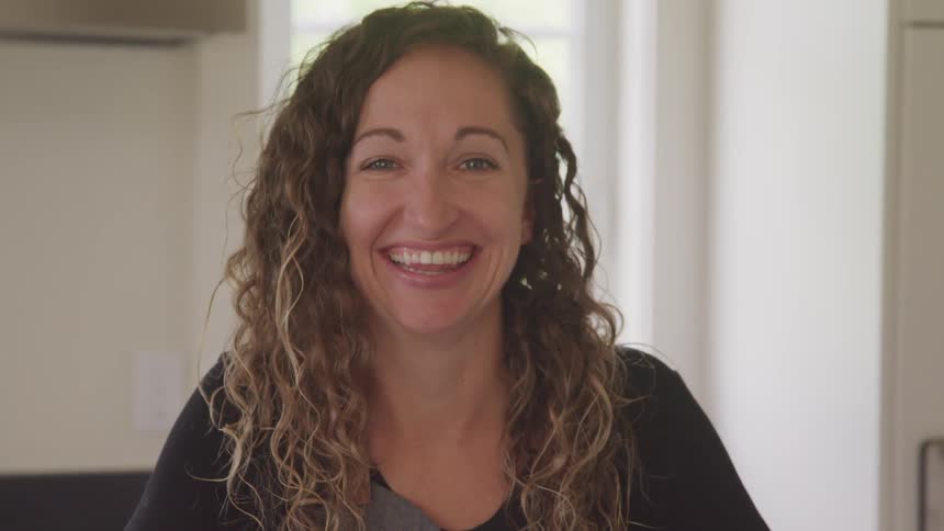 Young woman smiles and laughs looking at the camera from the kitchen at home