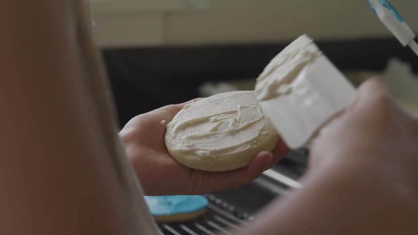 A person frosting cookies at home