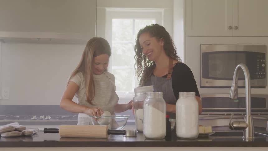 Mother and daughter measuring flour in a kitchen