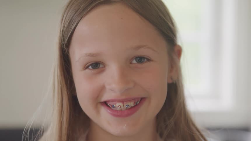 A young girl at home smiles for a portrait