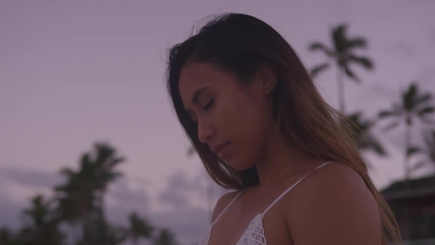 A woman is standing outdoors at dusk