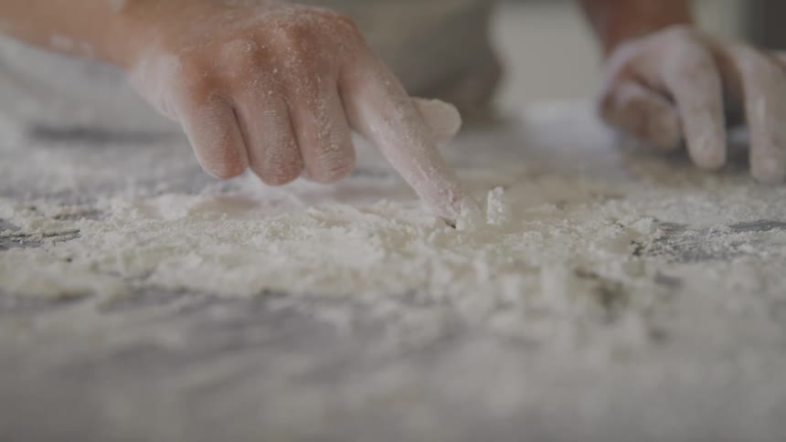 A person drawing in flour on a counter