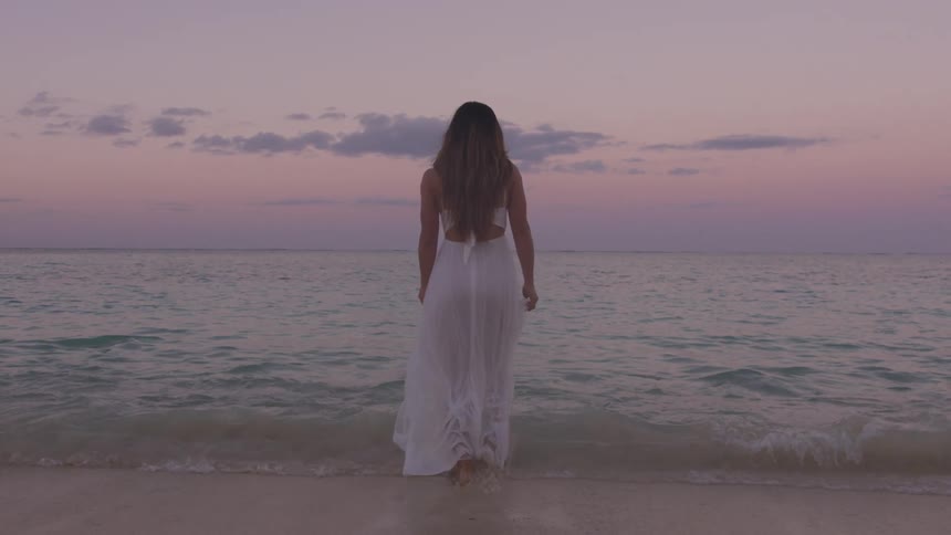 A woman in a dress walks in to the water
