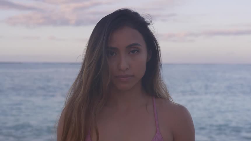 A woman poses on the beach at sunset