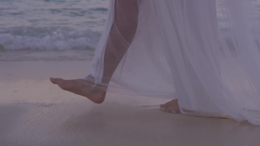 A woman walking down the beach next to the ocean