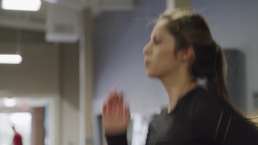 Woman runs on treadmill in blue walled gym