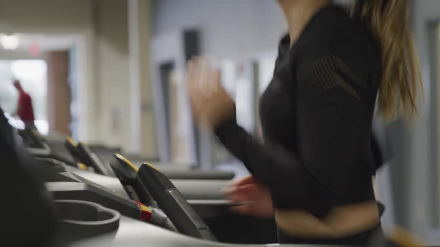 A woman jogs on a treadmill at a gym
