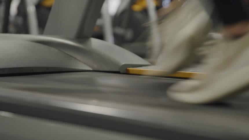 Woman wearing grey sneakers running on a treadmill in a gym