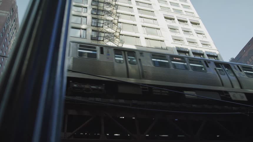 Subway train passes in front of a tall residential building in the citys downtown