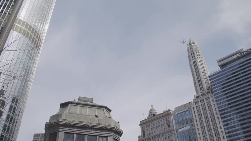 A city with buildings and skyscrapers with an airplane in the sky above