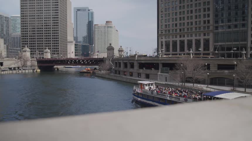 A crowded ferry travels along a channel through a metropolis during the day