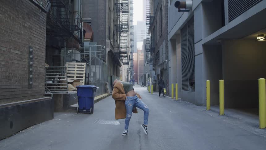 A woman in a alleyway dancing with buildings and the sky in the background