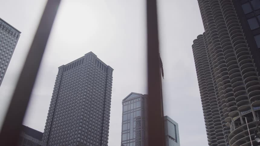 An american flag waves in the breeze surrounded by downtown city skyscrapers and buildings