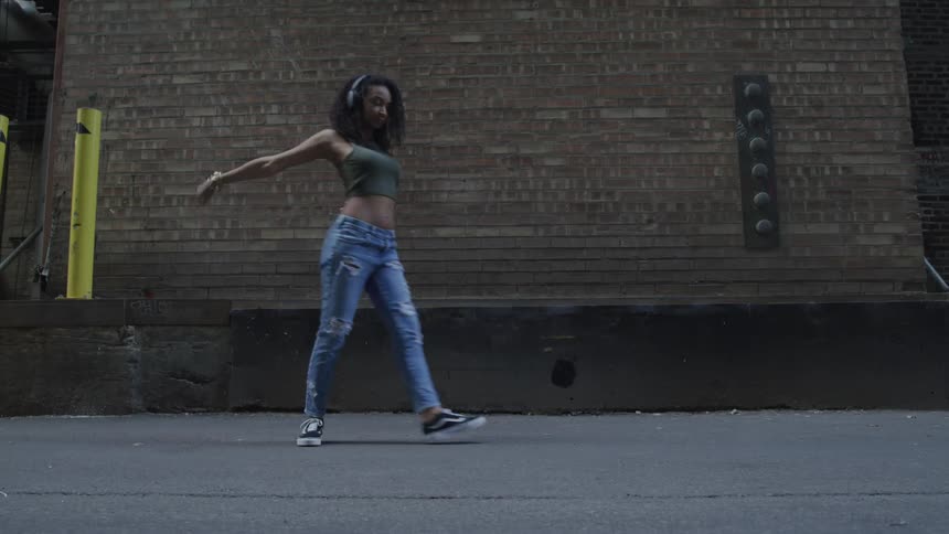 A woman is dancing outdoors on a street