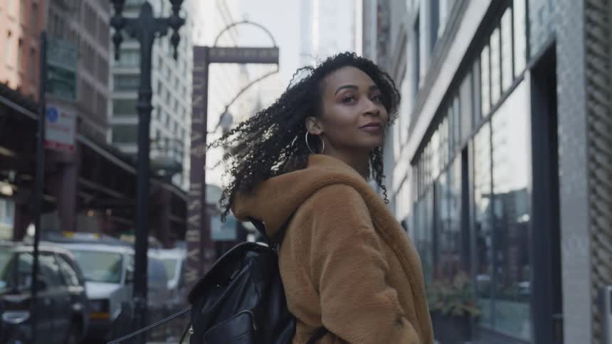 A woman walking down a sidewalk in the middle of the day