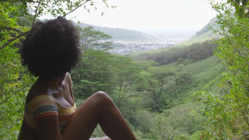 A woman is sitting outdoors in a forest