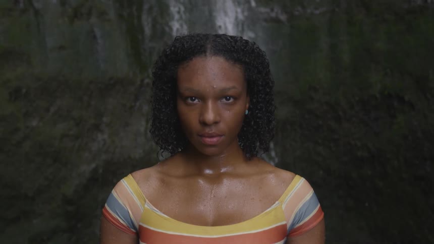 A teenage girl standing in front of a waterfall