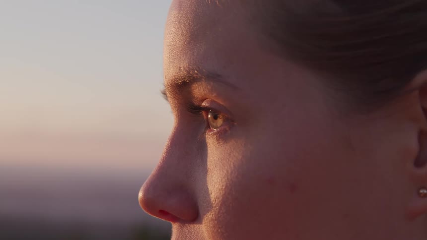 Side view of a woman with brown hair earrings as the sun shining on her face