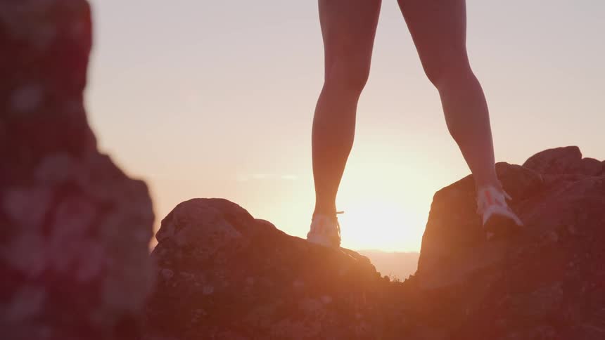 A hiker watches the sunrise from the top of a canyon
