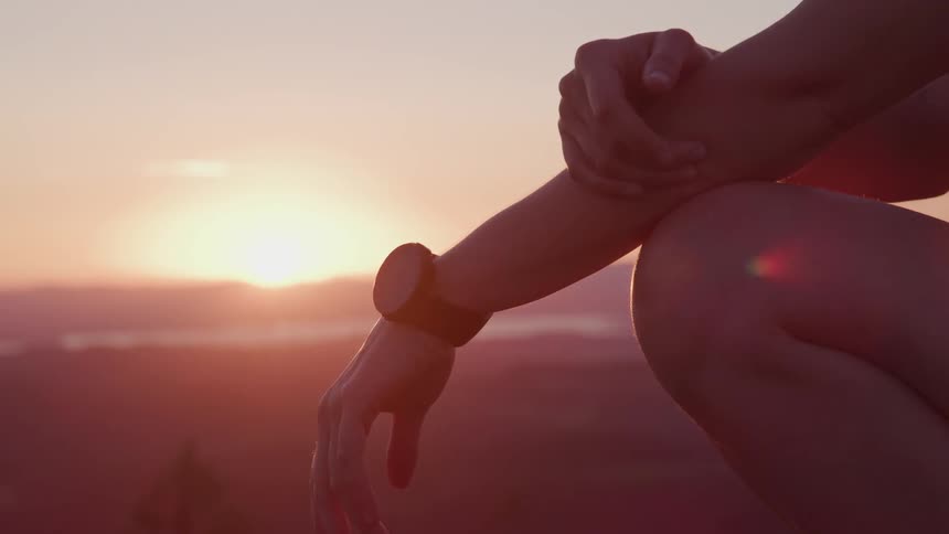 Woman kneeling in front of mountains at sunset