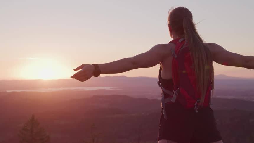 A female standing near mountains stretching and meditating