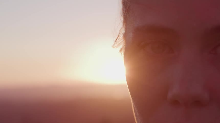 Wind blows through a womans hair as she poses outside at sunset