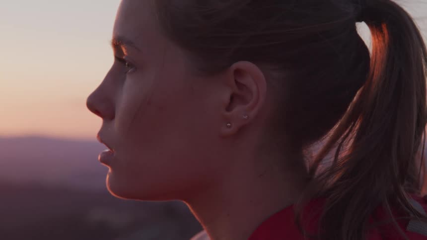A young female hiker looks out over the landscape in the evening