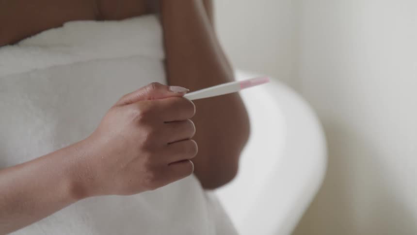 A woman in her bathroom looks at a pregnancy test