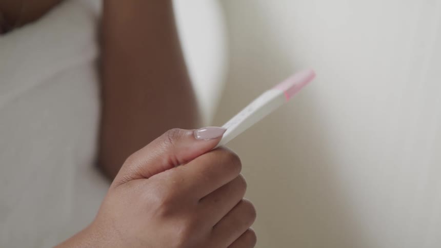 A woman wrapped in a towel examines a pregnancy test