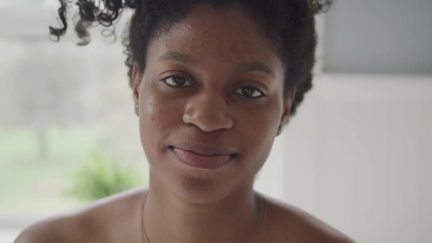 Black woman with curly messy bun faces the camera with eye contact