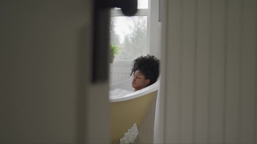 Young woman relaxes taking a bubble bath in a bathtub at home