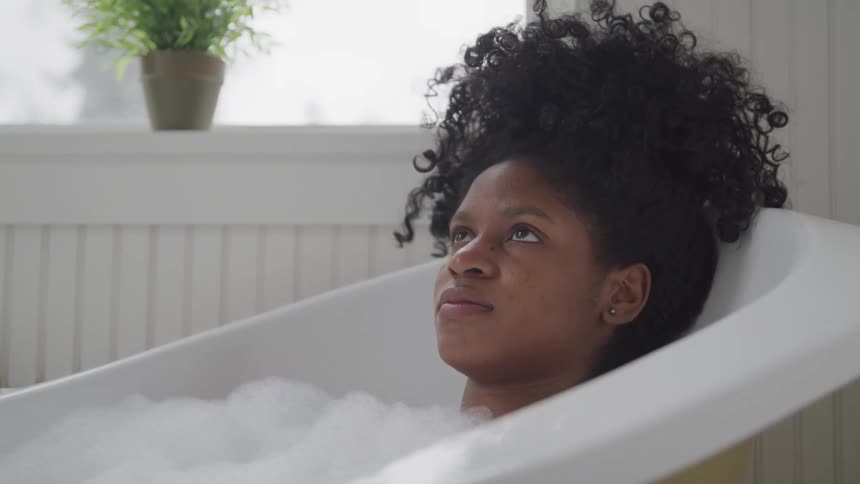 A black female soaking in a bathtub inside a room