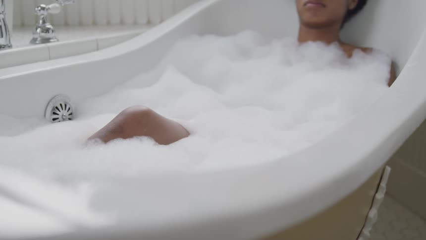 A young woman relaxes in a soapy bath