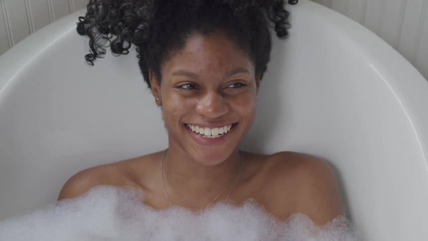 A woman is smiling in the bathtub