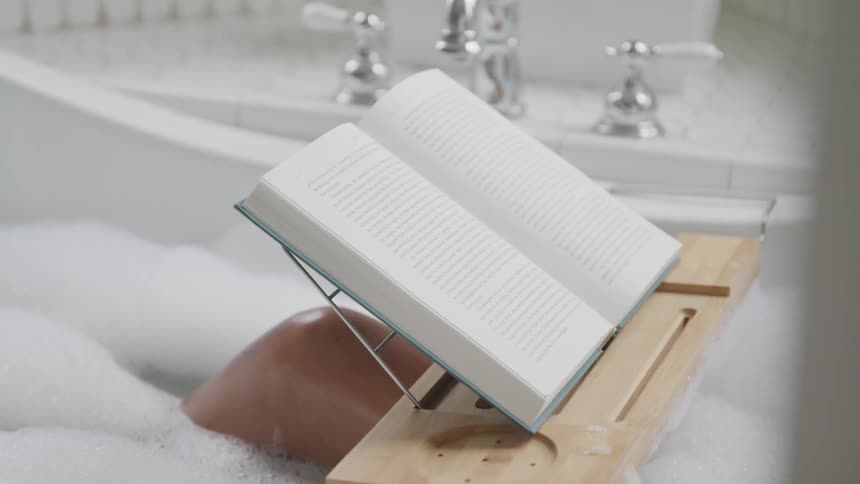 Woman reading book in bubble bath
