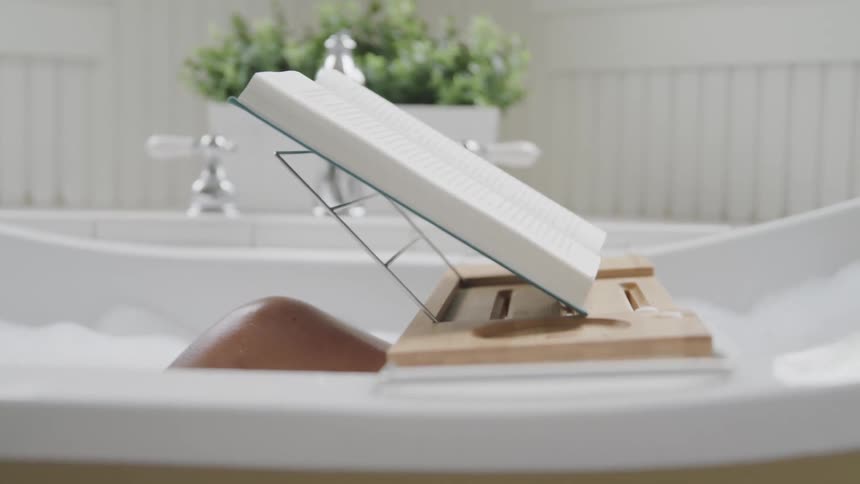 A person is reading while they are taking a bath