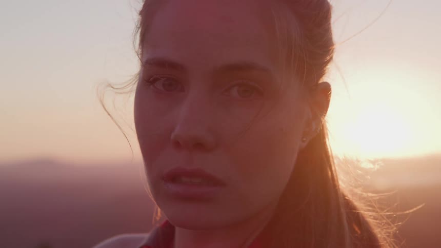 A woman is standing outdoors at dusk