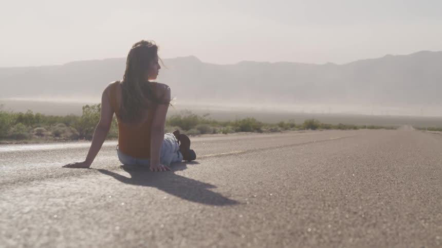 A teenager sitting in the middle of a road