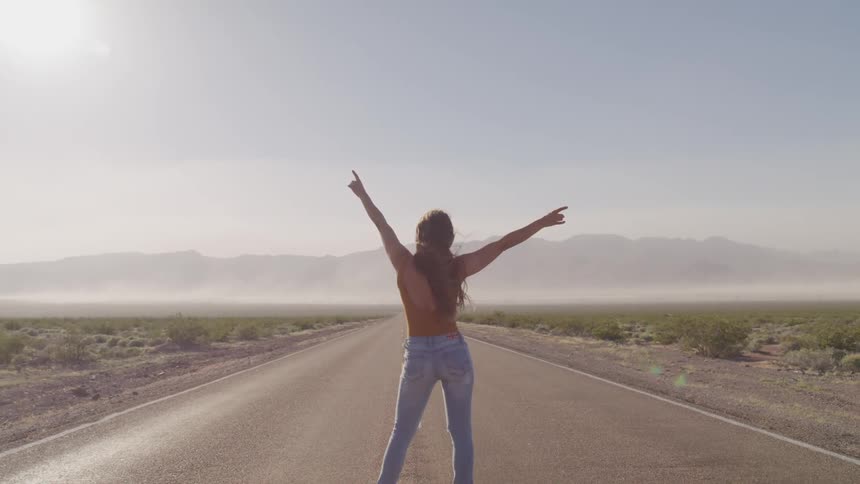 A woman is standing on a road in a rural area